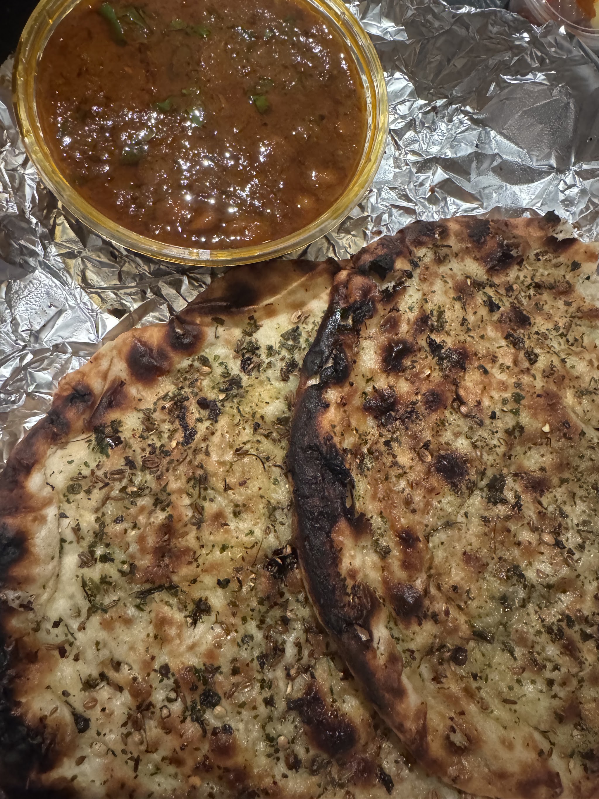 Charred garlic and herb naan beside a curry