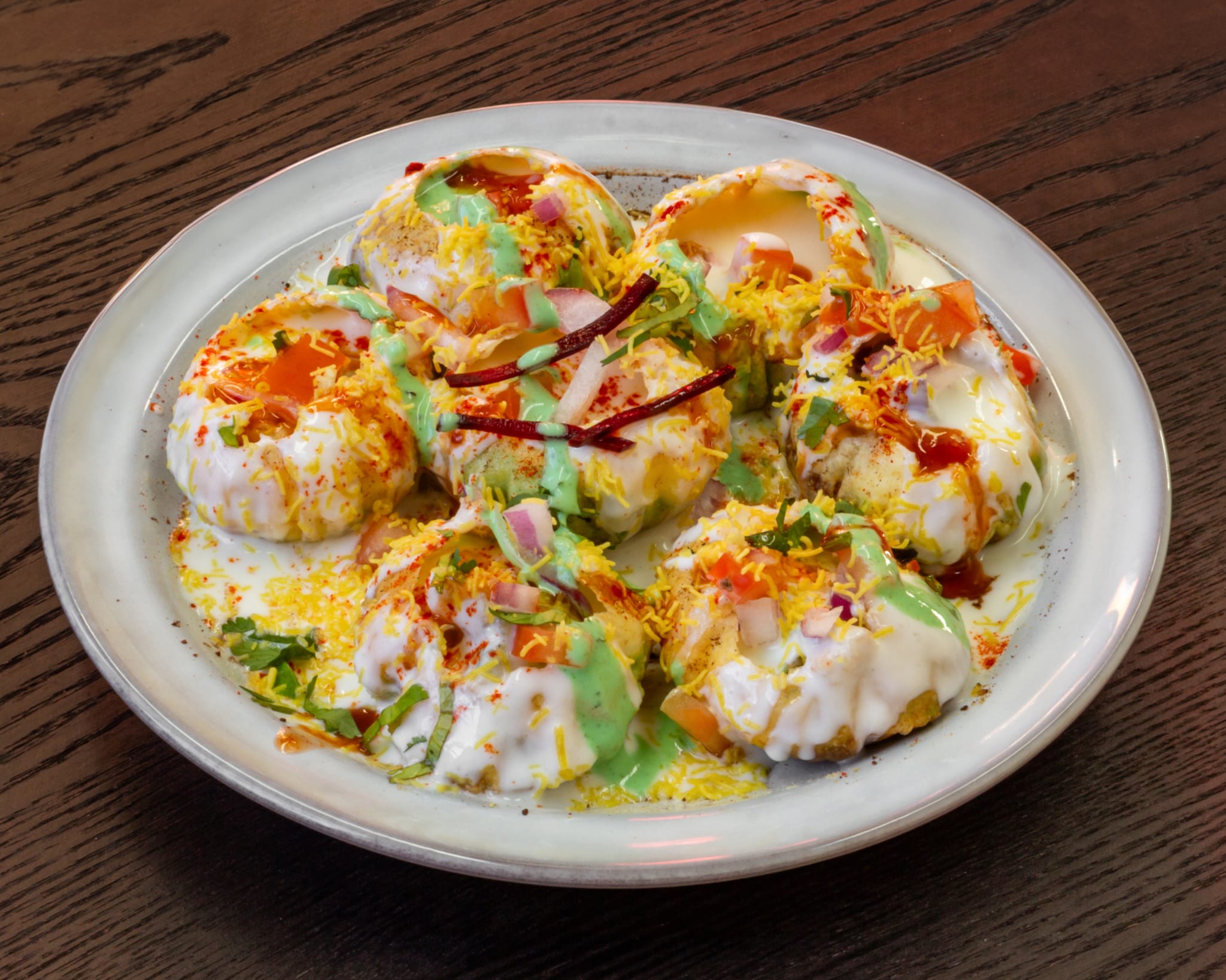 Dahi puri chaat topped with yoghurt, chutneys and sev